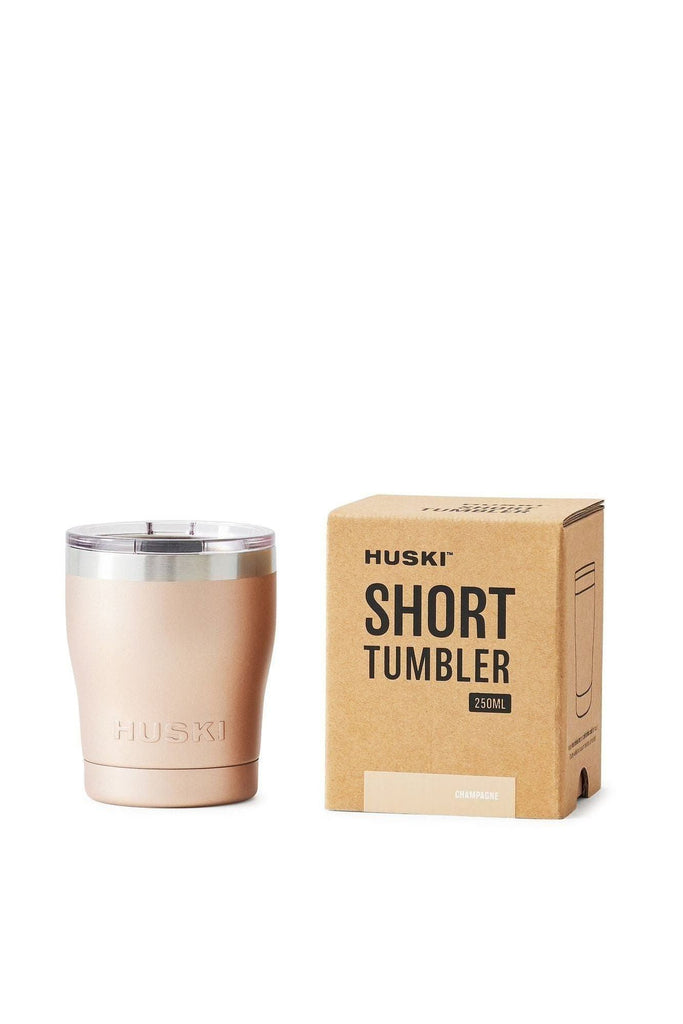 Huski Short tumbler in champagne colourway with a silver ring around the top of the tumbler and a clear lid sitting next to its packaging box on a white background.