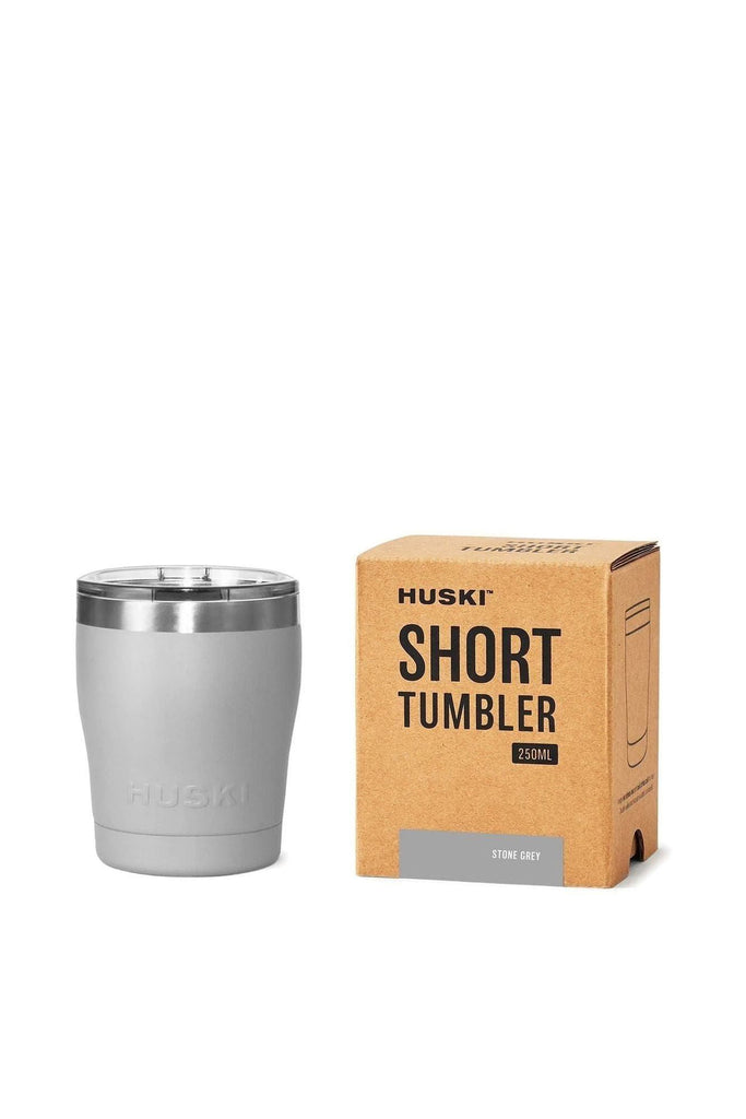Huski Short Tumbler 2.0 in Stone Grey colourway with a silver rim and clear lid. Sitting next to its packaging on a white background.