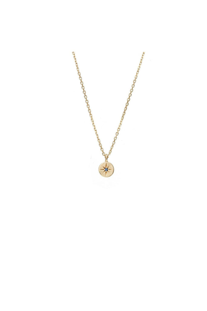 Gold necklace with a small pendant called North Star from New Zealand label Silk & Steel with a blue sapphire gemstone in the middle on a white background