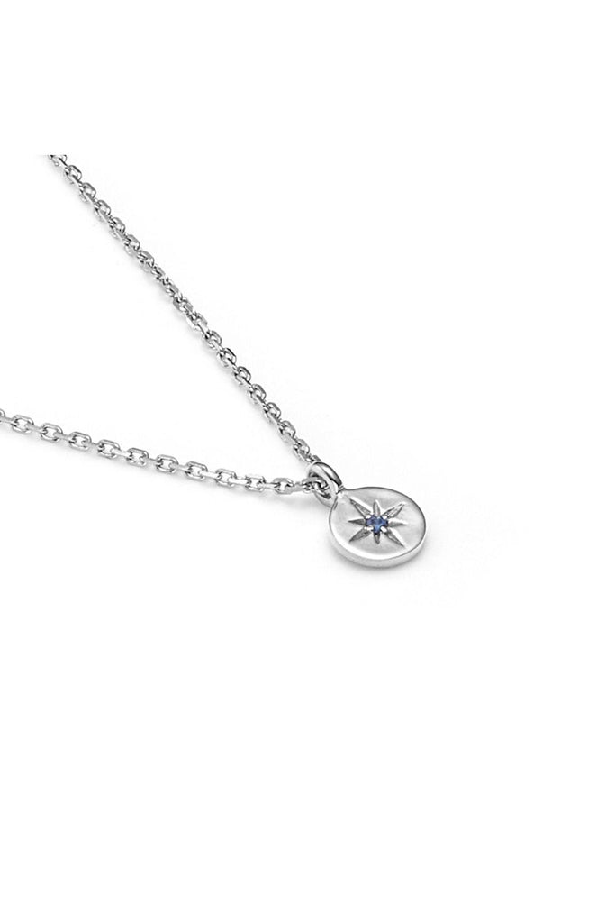Silver necklace with a small pendant called North Star from New Zealand label Silk & Steel with a blue sapphire gemstone in the middle on a white background