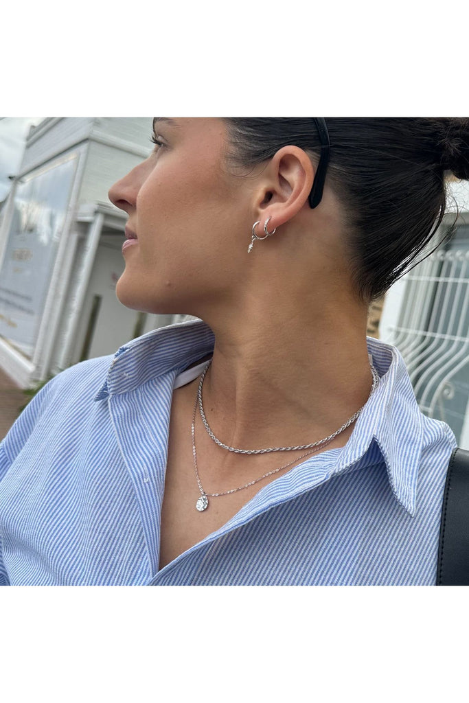 Woman wearing a blue striped shirt and silver jewelry outdoors. Ever Harmony Necklace in Silver.