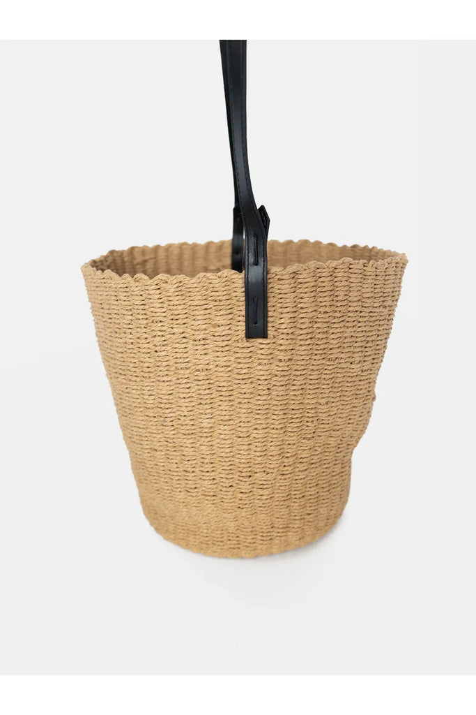 Woven basket with a black handle on a white background. Sophie Bring It Bag in Natural.