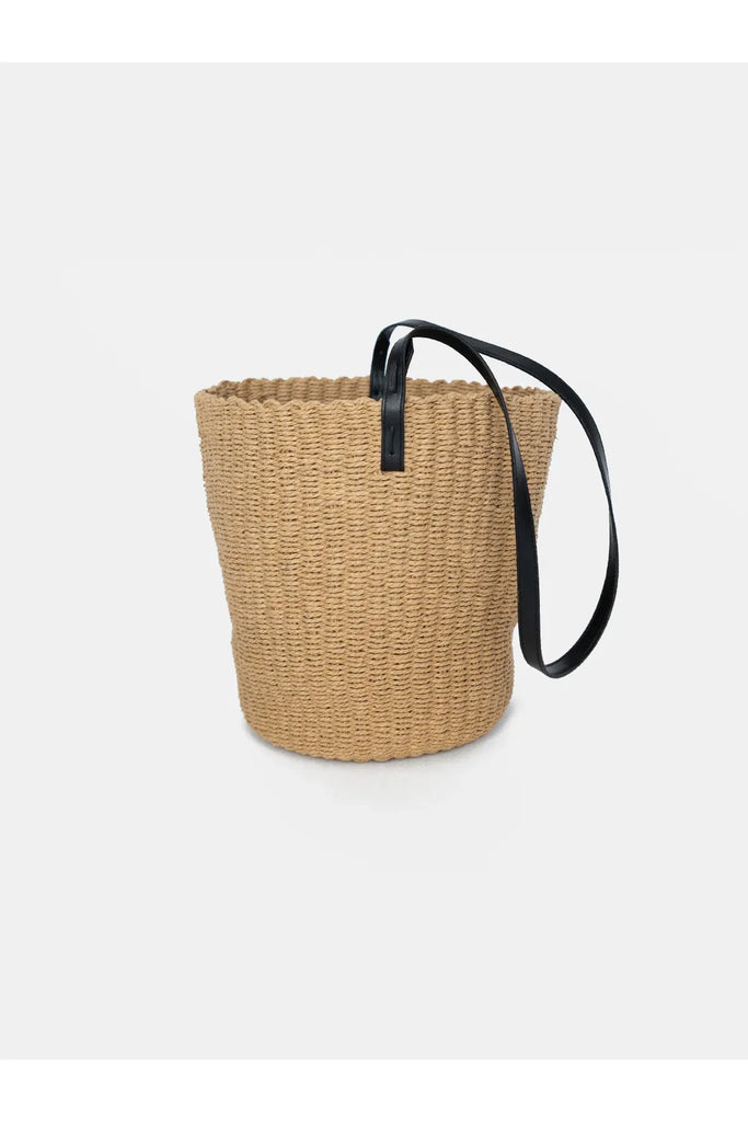 Woven basket with a black handle on a white background. Sophie Bring It Bag in Natural.