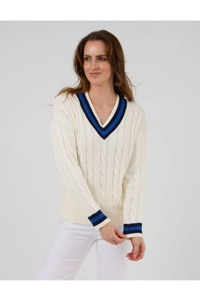 Woman wearing a white sweater with blue accents on a plain background. Stella and Gemma Courtside Jumper Off White.