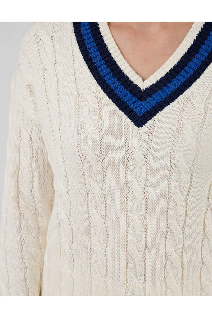Woman wearing a white sweater with blue accents on a plain background. Stella and Gemma Courtside Jumper Off White.
