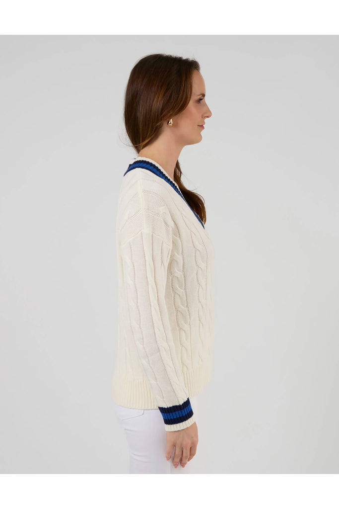Woman wearing a white sweater with blue accents on a plain background. Stella and Gemma Courtside Jumper Off White.