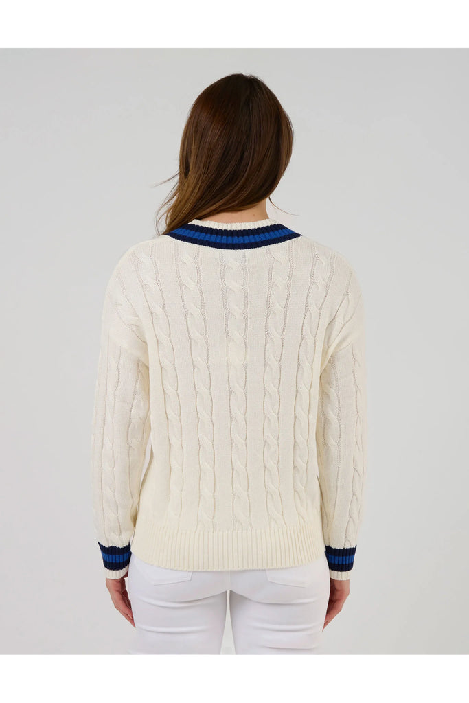 Woman wearing a white sweater with blue accents on a plain background. Stella and Gemma Courtside Jumper Off White.