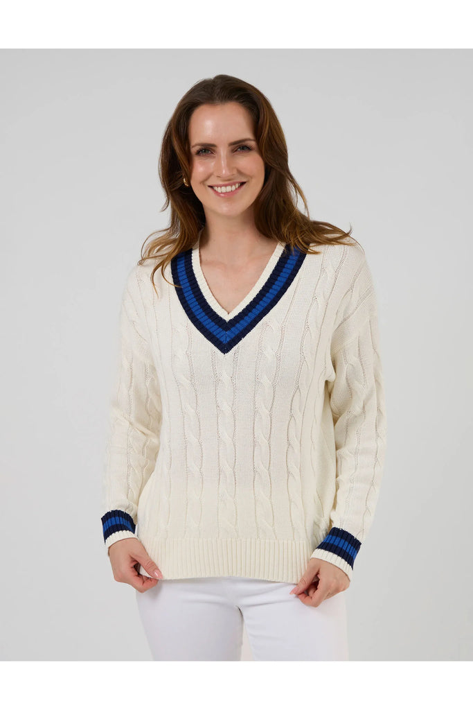 Woman wearing a white sweater with blue accents on a plain background. Stella and Gemma Courtside Jumper Off White.