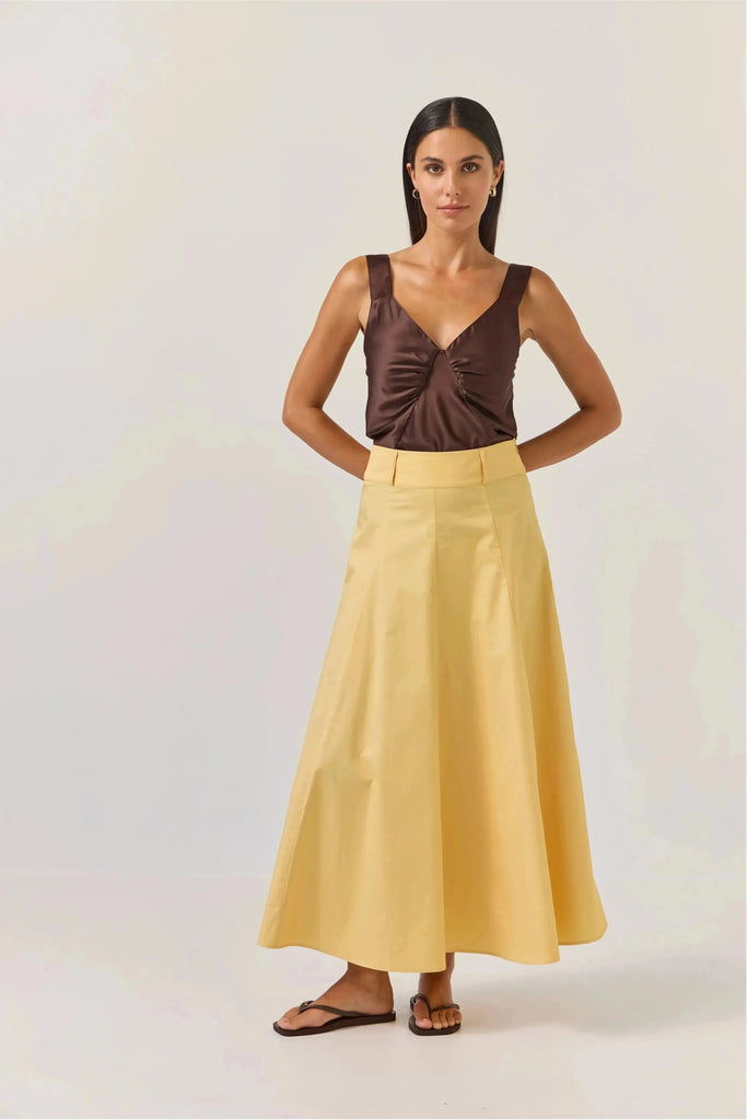 Woman wearing a brown satin top and Tuesday Label Circle Skirt in gold on a white background