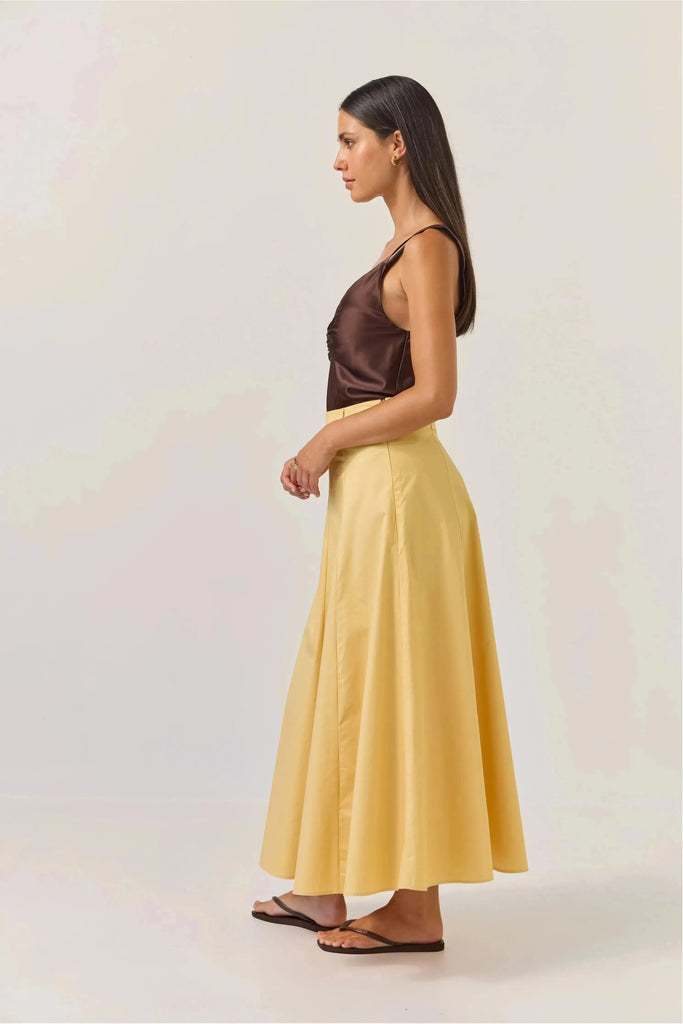 Woman wearing a brown satin top and Tuesday Label Circle Skirt in gold on a white background