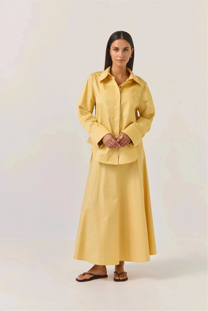 Woman wearing a gold shirt and Tuesday Label Circle Skirt in gold on a white background