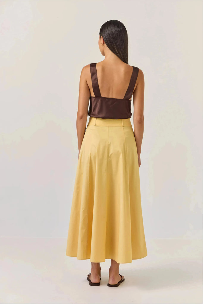 Woman wearing a brown satin top and Tuesday Label Circle Skirt in gold on a white background
