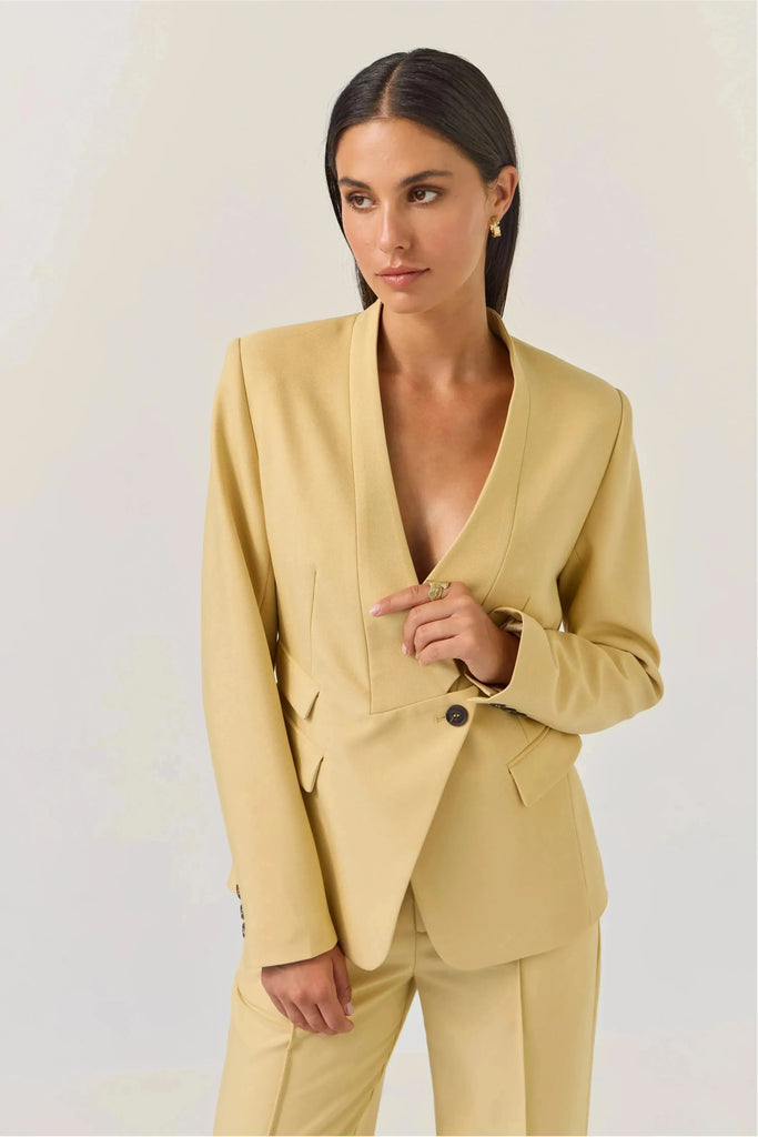 Woman wearing a Tuesday Label Tuxedo Blazer, butter lemon with a matching pant on a plain background