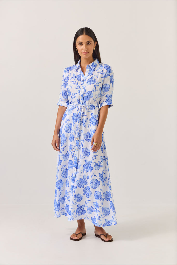Woman wearing a blue floral dress on a white background. Tuesday Label Nicola dress in Blue Rose. 