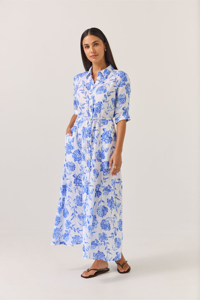Woman wearing a blue floral dress on a white background. Tuesday Label Nicola dress in Blue Rose. 