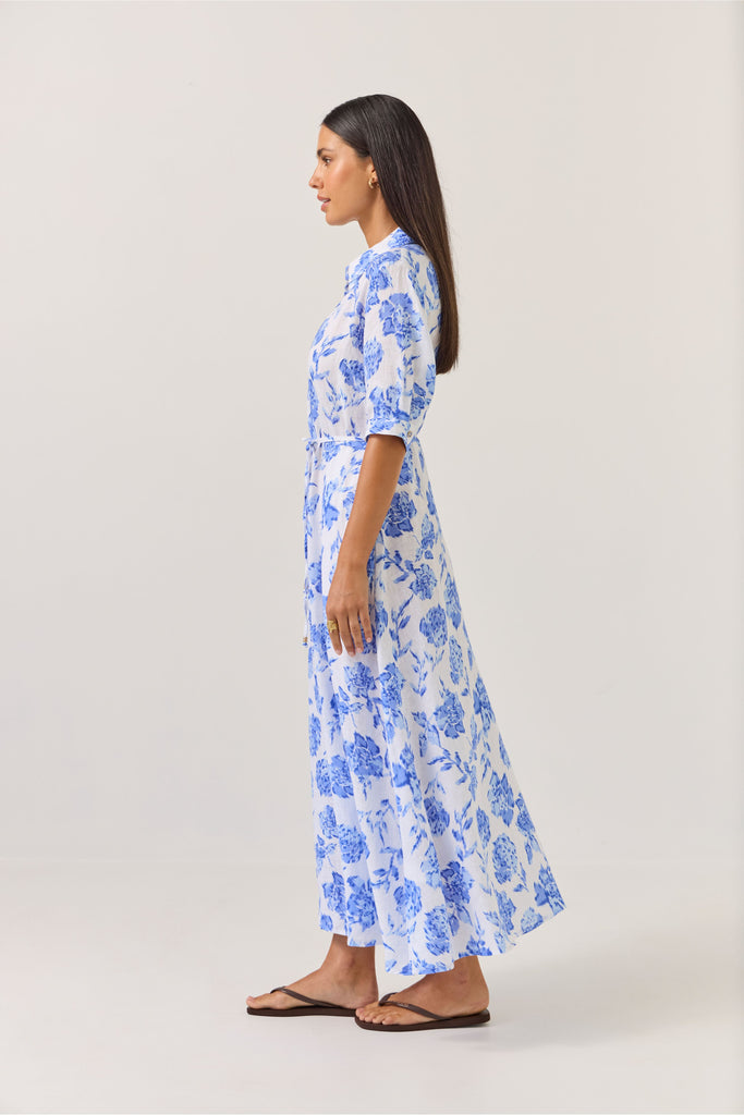 Woman wearing a blue floral dress on a white background. Tuesday Label Nicola dress in Blue Rose. 