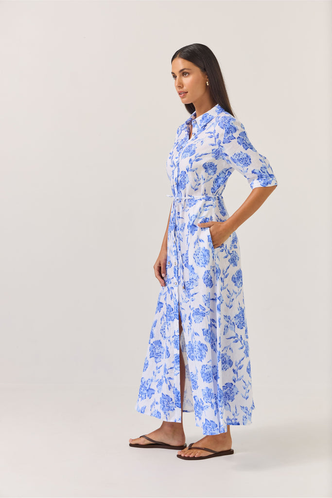 Woman wearing a blue floral dress on a white background. Tuesday Label Nicola dress in Blue Rose. 