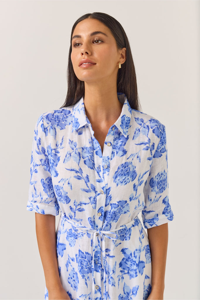 Woman wearing a blue floral dress on a white background. Tuesday Label Nicola dress in Blue Rose. 