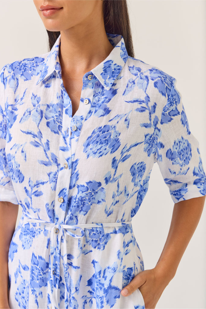 Woman wearing a blue floral dress on a white background. Tuesday Label Nicola dress in Blue Rose. 