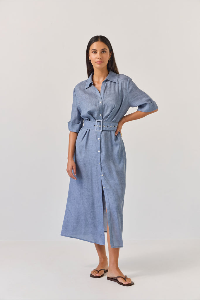 Woman wearing a blue dress with a belt on a white background. Tuesday Label Sunray dress.