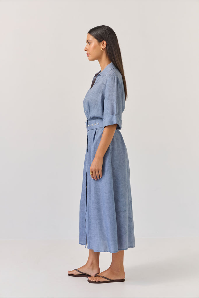 Woman wearing a blue dress with a belt on a white background. Tuesday Label Sunray dress.