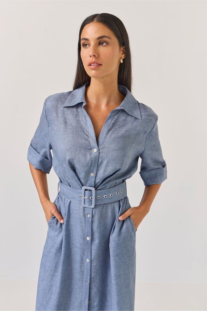 Woman wearing a blue dress with a belt on a white background. Tuesday Label Sunray dress.
