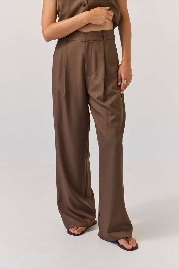 Person wearing brown high-waisted pants on a white background. Tuesday Label Boyfriend Pant in Bitter Chocolate with matching vest.