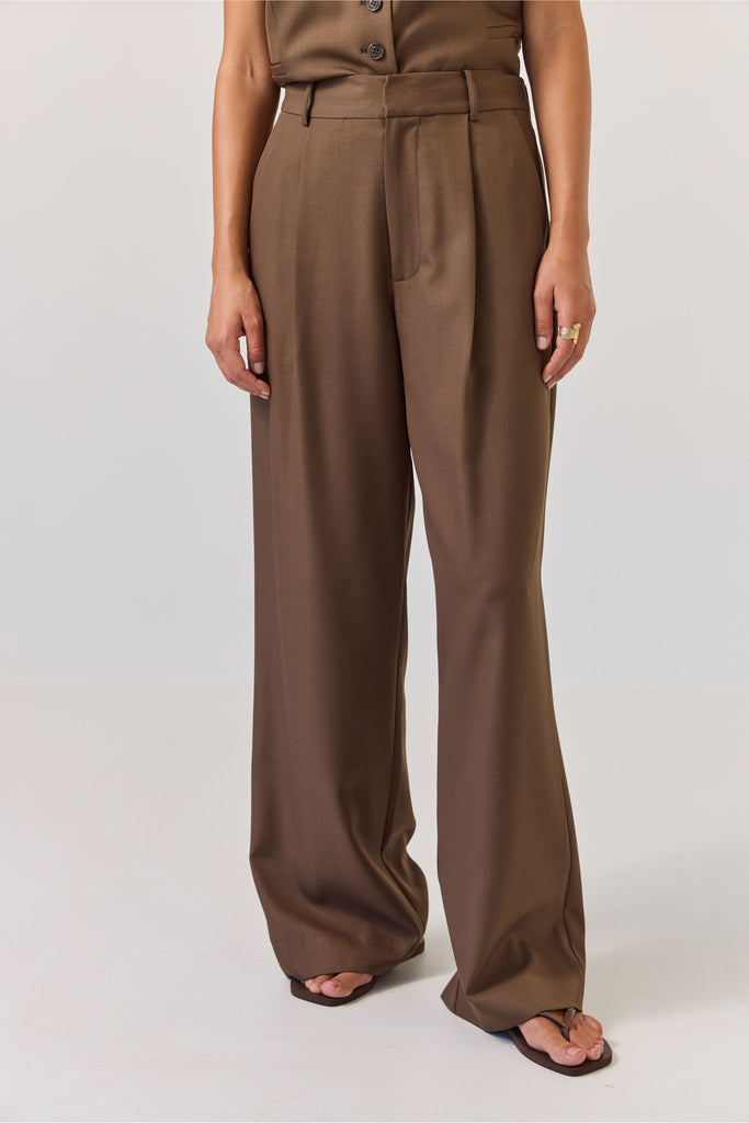 Person wearing brown wide-leg pants on a white background