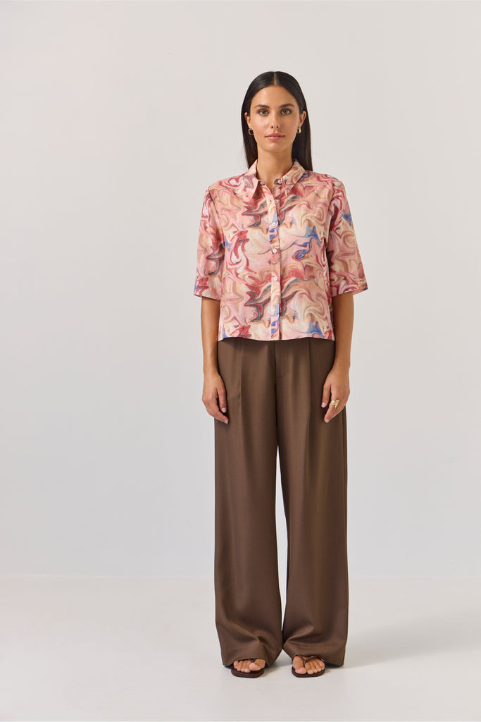 Woman wearing a floral blouse and brown pants on a white background