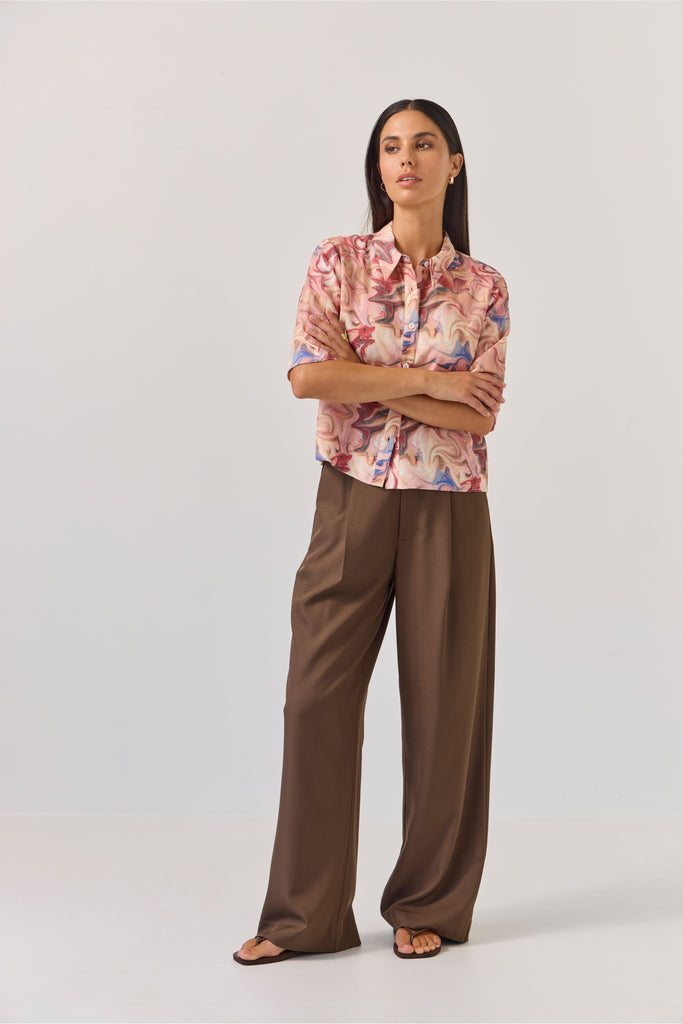 Woman wearing a floral blouse and brown pants on a white background