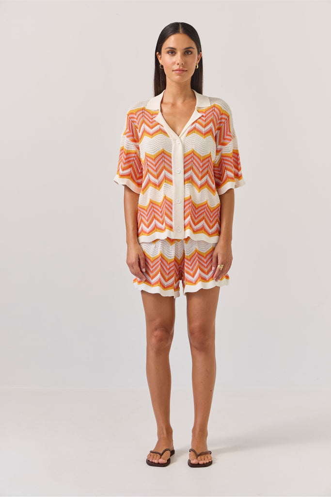 Woman wearing a colourful zigzag patterned matching shirt and shirts on a white background. Tuesday Label Revere Top and Umpire Shorts in chevron pattern.