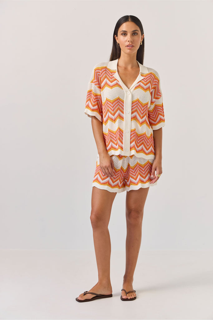 Woman wearing a colourful zigzag chevron patterned top and shorts on a white background. Tuesday Label Revere Top and Umpire Shorts.