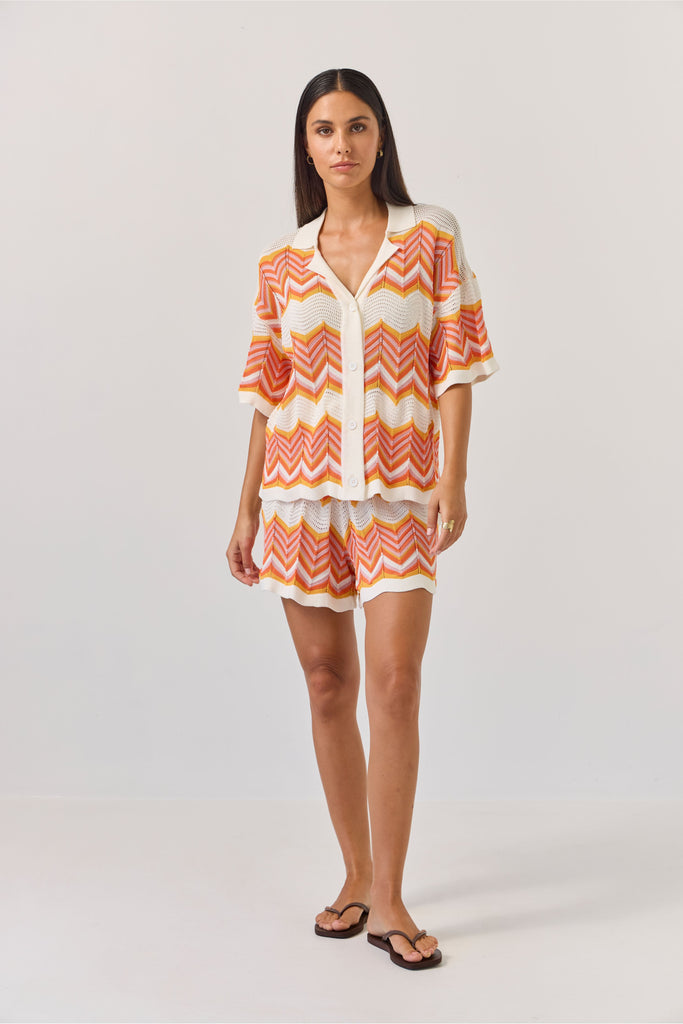 Woman wearing a colourful zigzag chevron patterned top and shorts on a white background. Tuesday Label Revere Top and Umpire Shorts.