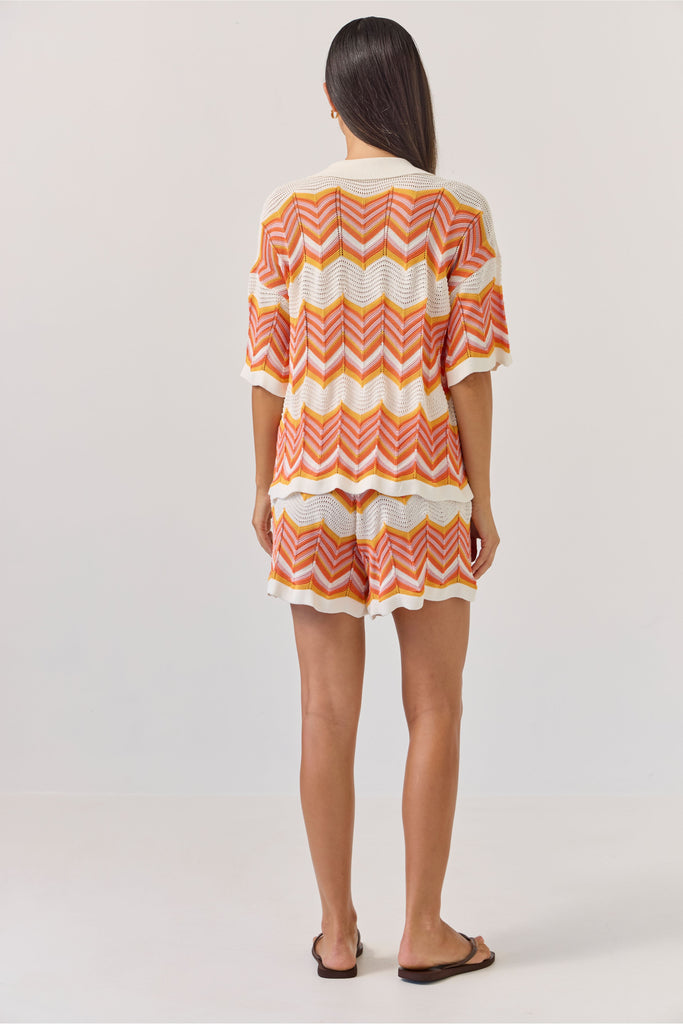 Woman wearing a colourful zigzag patterned matching shirt and shirts on a white background. Tuesday Label Revere Top and Umpire Shorts in chevron pattern.