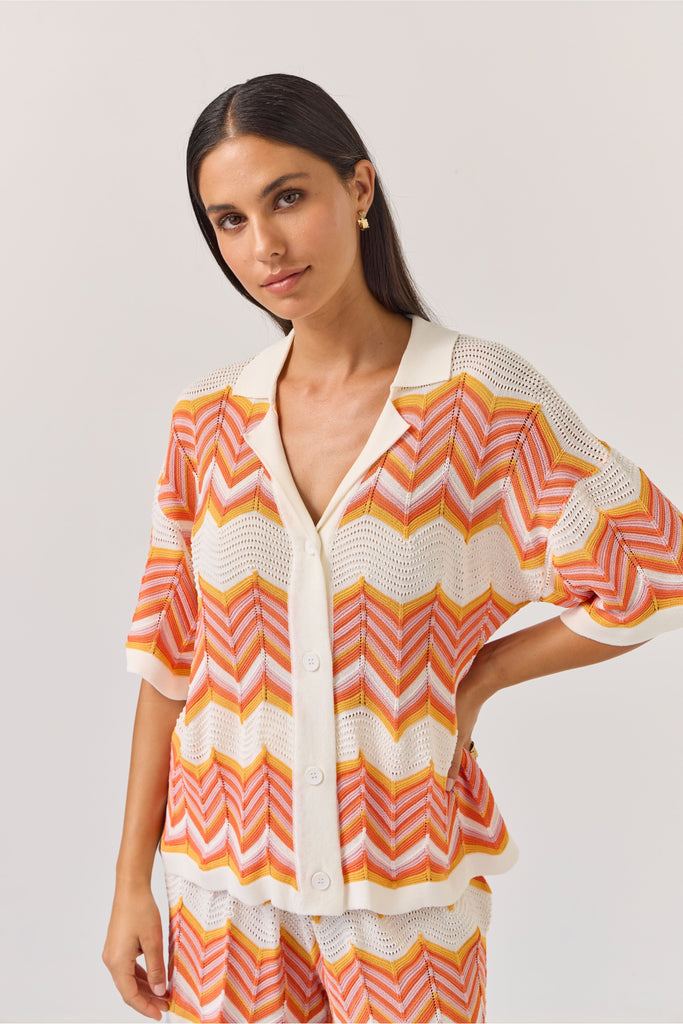 Woman wearing a colourful zigzag chevron patterned top and shorts on a white background. Tuesday Label Revere Top and Umpire Shorts.