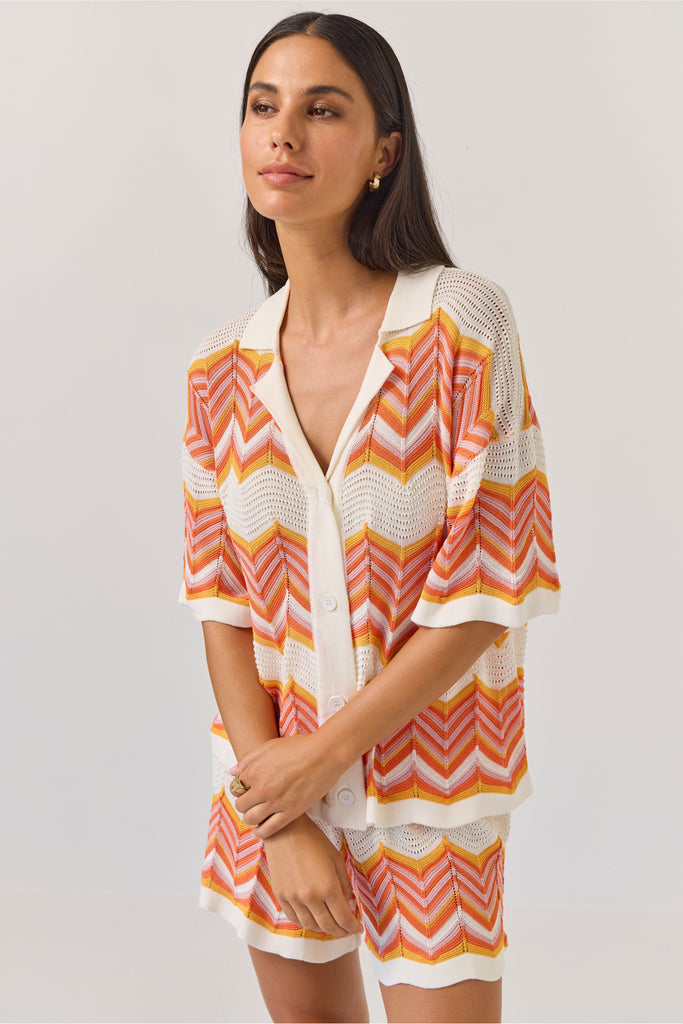 Woman wearing a colourful zigzag patterned matching shirt and shirts on a white background. Tuesday Label Revere Top and Umpire Shorts in chevron pattern.