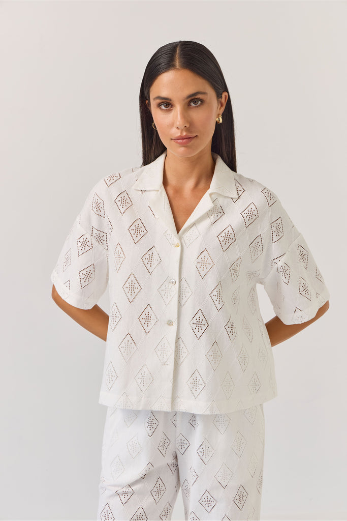 Woman wearing a white patterned matching embossed shirt and pant on a plain background
