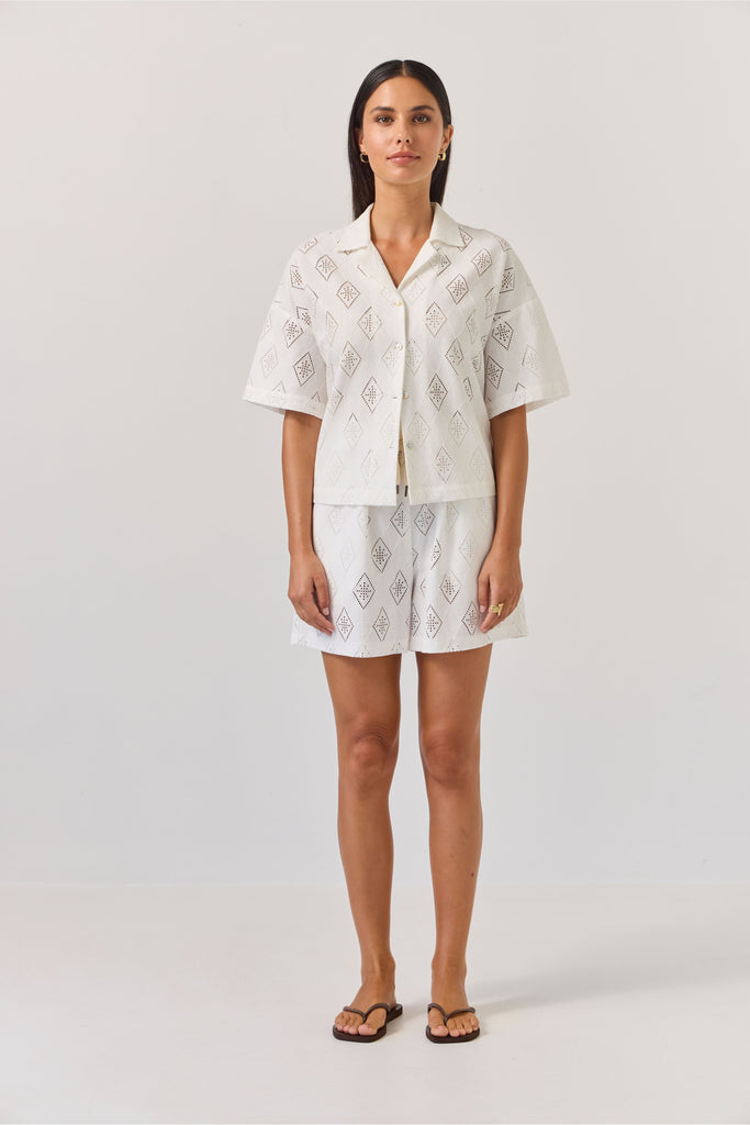 Woman wearing a white patterned matching embossed shirt and Short on a plain background