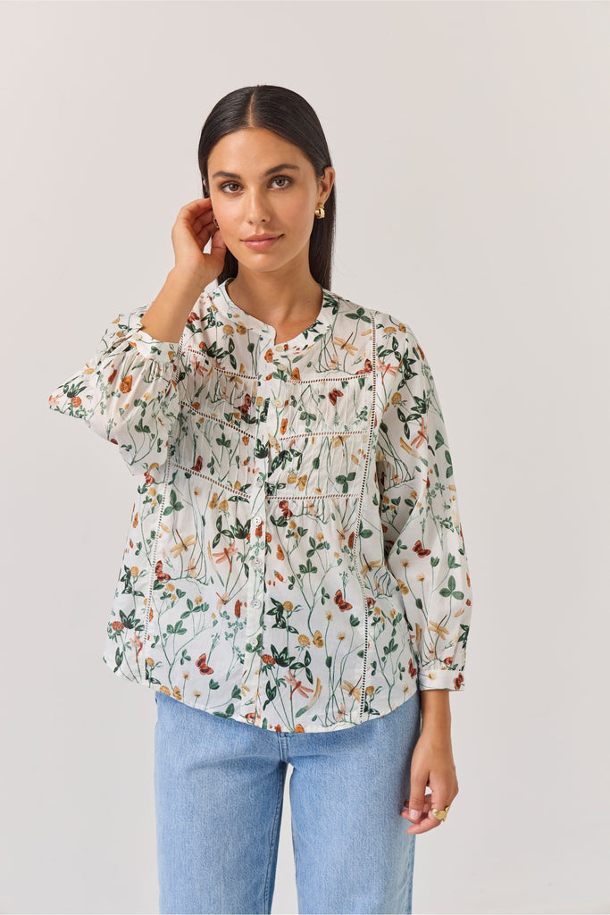 Woman wearing a floral blouse and blue jeans against a plain background. Tuesday Label Maeve Floral Top.