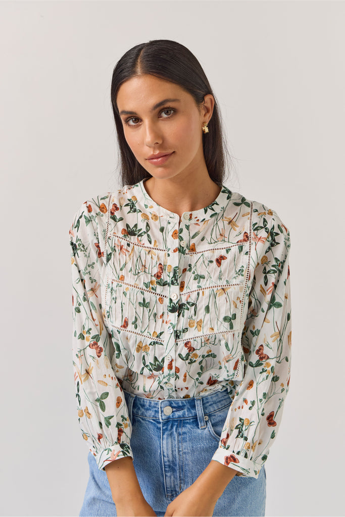 Woman wearing a floral blouse and blue jeans against a plain background. Tuesday Label Maeve Floral Top.