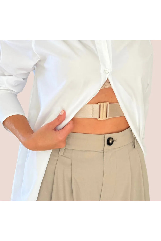 Person wearing a white shirt and beige pants with a belt, on a plain background