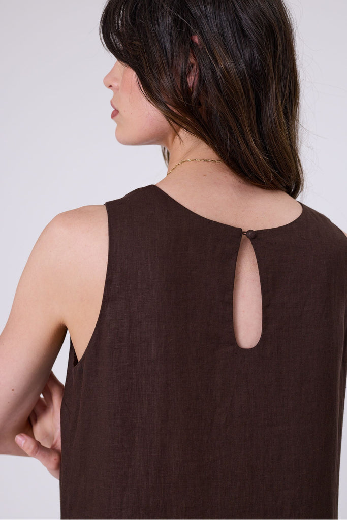 Woman wearing a brown dress with ruffled hem on a white background. Marlow Verona Linen Dress in Carob.