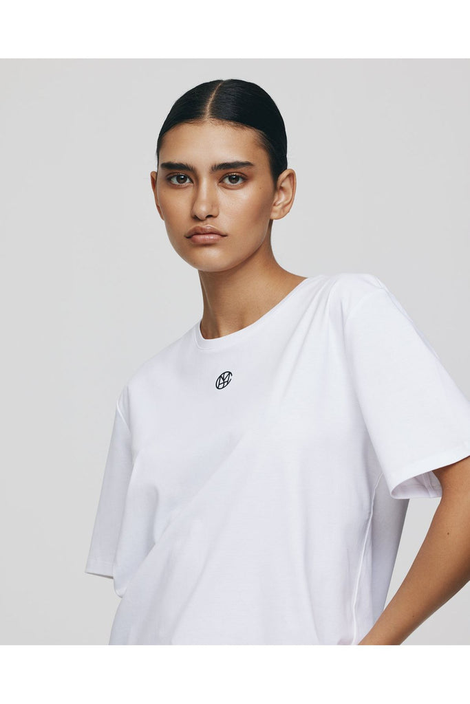 Person wearing a white t-shirt with a small logo on a plain background. MSCH Copenhagen Melea Icon Tee in White with a black logo