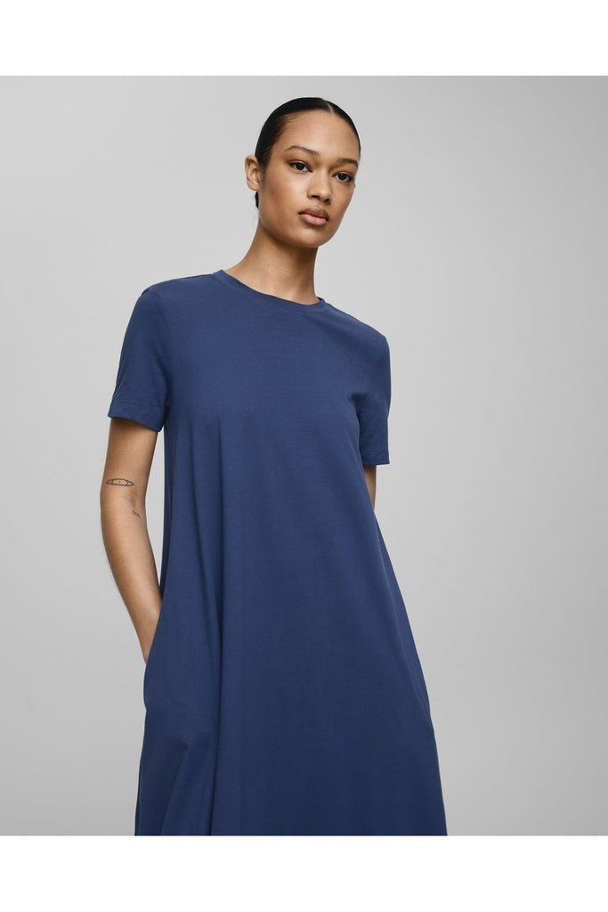 Woman wearing a blue dress on a grey background. MSCH Copenhagen Olga Organic SS dress in Oceana Blue