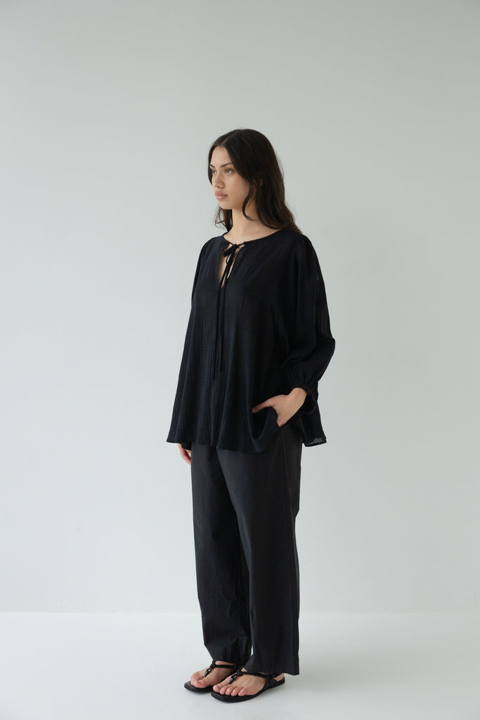 Woman wearing a black outfit on a white background. Sophie Tie Top in black Check.