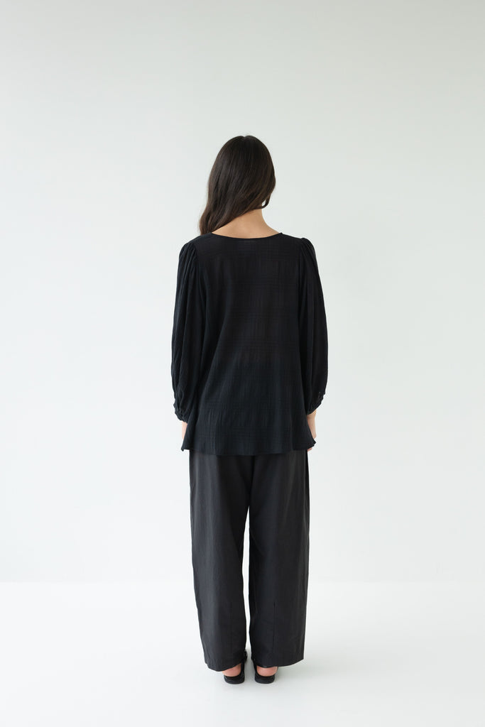 Woman wearing a black outfit on a white background. Sophie Tie Top in black Check.