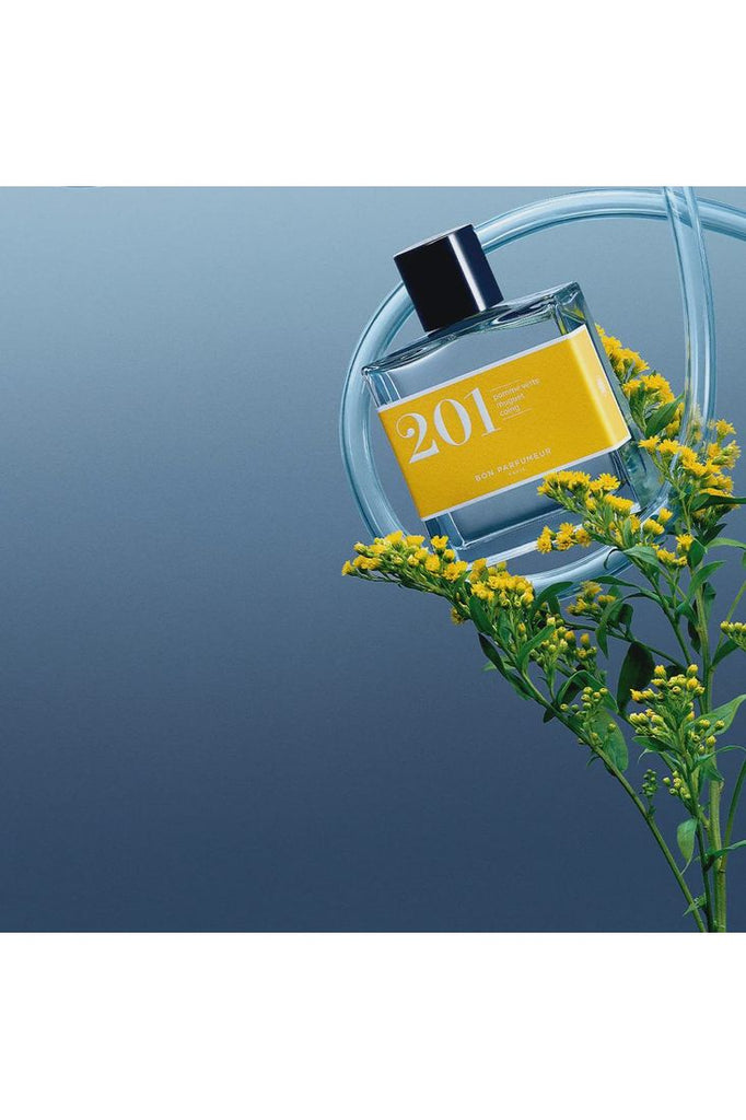 Bon Parfumeur bottle of Eau de Parfum 201 artistically displayed against Lily of the Valley