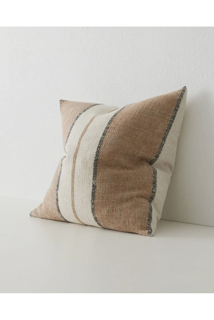 Warwick NZ Weave NZ Ottavio Cushion sitting against a white wall.  Side image showing chunky, textured stripe in Cocoa shade, combining spiced brown with beige and onyx stripes, perfect for a warm or rustic style.